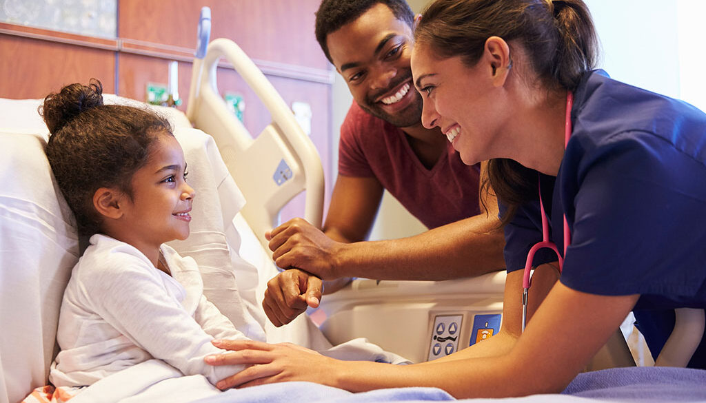 A Young African American Child Smiling at Her Dad & a Pediatrician Standing Beside Her While Laying in a Hospital Bed Pediatric Pain Management