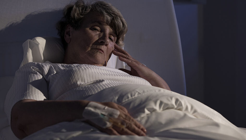 Closeup of a Senior Woman Laying in Bed Sick at Night Communicating With Hospice After Hours