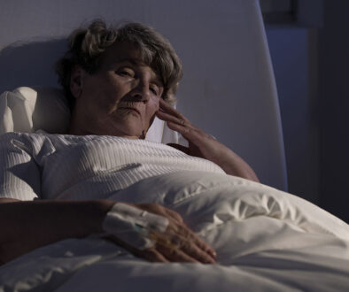 Closeup of a Senior Woman Laying in Bed Sick at Night Communicating With Hospice After Hours