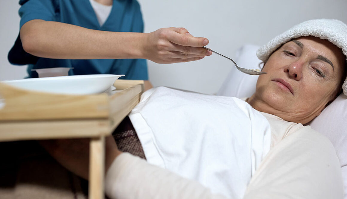 A Terminally Ill Woman Turning Her Face Away From a Spoon of Food Being Served by a Nurse Hospice Patient Not Eating