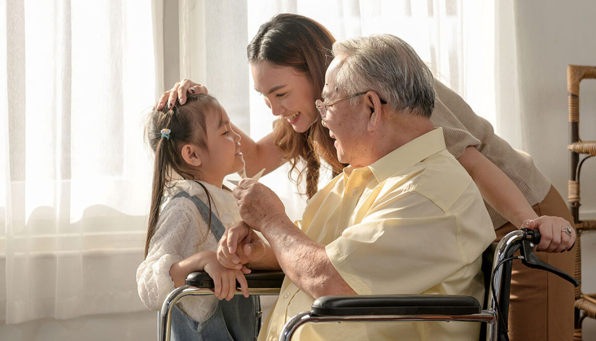 A Senior Man Sitting in a Wheelchair Smiling With His Daughter and Granddaughter Beside Him Benefits of Inpatient Hospice for Families